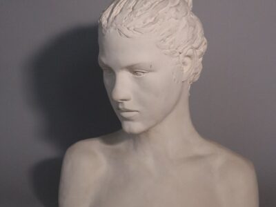 a sculpture of a teenage girl, her hair in a bun, in white plaster